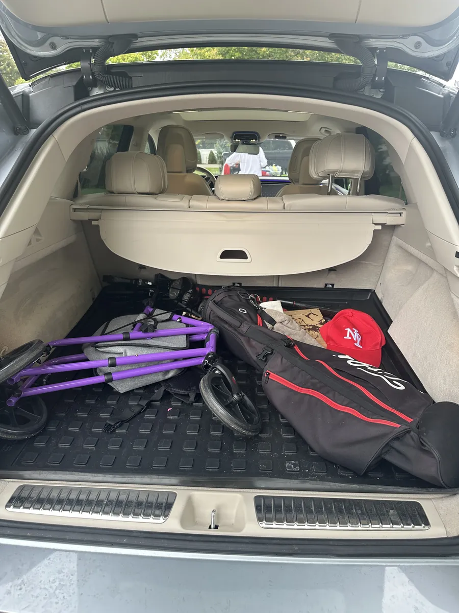 Before: an SUV cargo area full of gear on a dirty black liner